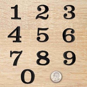 A set of Black 0-9 Numbers Iron On Patches 1-1/4"H - Sold Separately on a wooden surface.