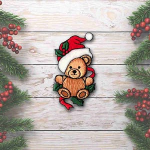 A Christmas Bear Patches (2-Pack) Christmas Embroidered Iron on Patch wearing a santa hat on a wooden background.