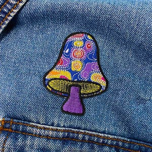 A Swirly Magical Mushroom embroidered patch on a denim jacket.