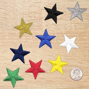 Ten 1.5 Inch Star Iron On Patches on a wooden surface.
