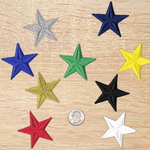 Five 2 Inch Star Iron on Patch (5 Pack) appliques on a wooden table.