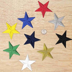 Five 3 Inch Iron on Star Patches (5 Pack) appliques on a wooden table.