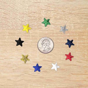A set of .5 Inch Star Iron On Patches (10 Pack) on a wooden table.