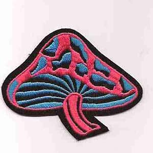 A Black Light looking Pink and Blue Velvet Mushroom Iron On Patch on a white surface.