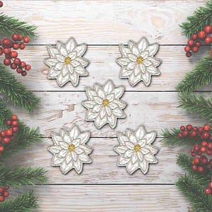 Five (5 Pack) Christmas Sparkly Layered Poinsettia Iron On Patch in White on a wooden background.