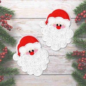 Two Santa Claus Face Patches (2 Pack) Christmas Embroidered Iron On Patch Appliques on a wooden background.