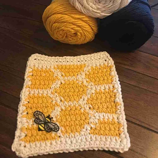 A crocheted dishcloth with Bee Patches with Chiffon Wings (5 Pack) Insect Embroidered Iron on Patch Appliques on it.
