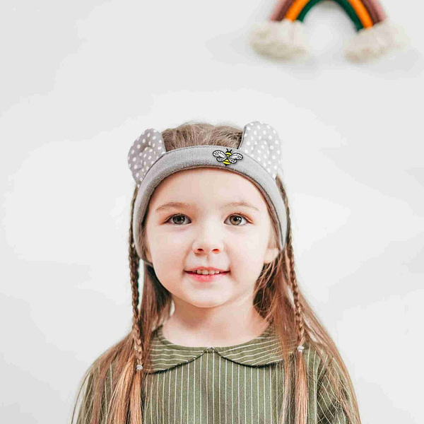 A little girl wearing Bee Patches with Chiffon Wings (5 Pack) Insect Embroidered Iron on Patch Appliques headband in front of a rainbow.