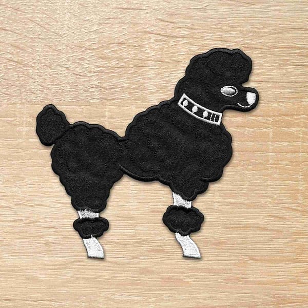 A 50's Poodle Embroidered Iron On Patch on a wooden surface.