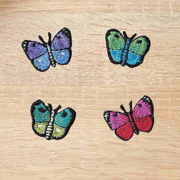 Four Tiny Butterfly Iron on Patches: Multiple Colors embroidered patches on a wooden table.