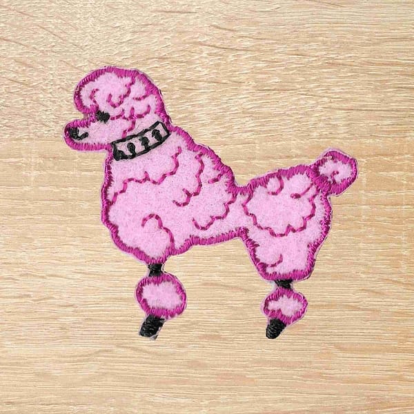 A 50's Poodle Embroidered Iron On Patch appliqued on a wooden surface.