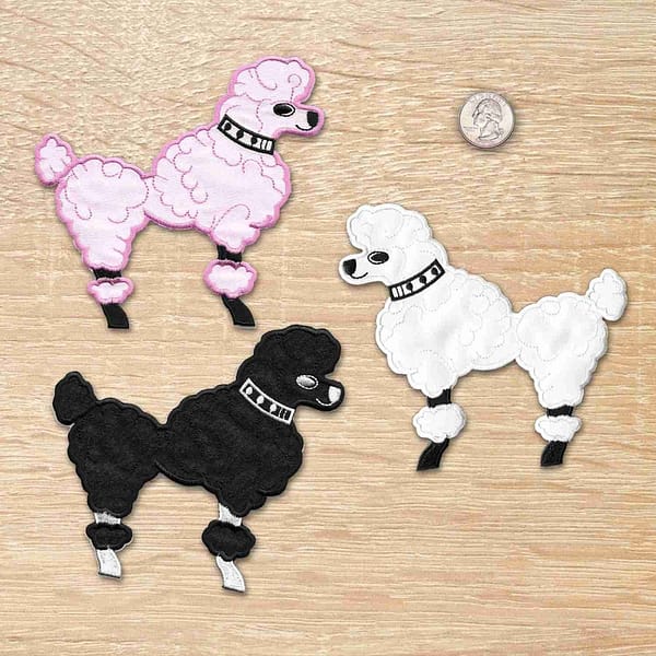 Three black and pink 50's Poodle Embroidered Iron On Patch on a table.