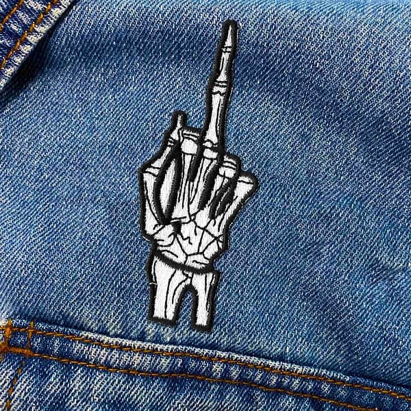 A Skeleton Middle Finger Iron on Patch embroidered patch on a denim jacket.