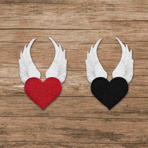Two Winged Heart Iron On Patches on a wooden surface.