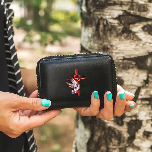 A woman holding a black wallet with a Cross with Dove Patches (5-Pack) Religious Embroidered Iron On Patch Applique on it.