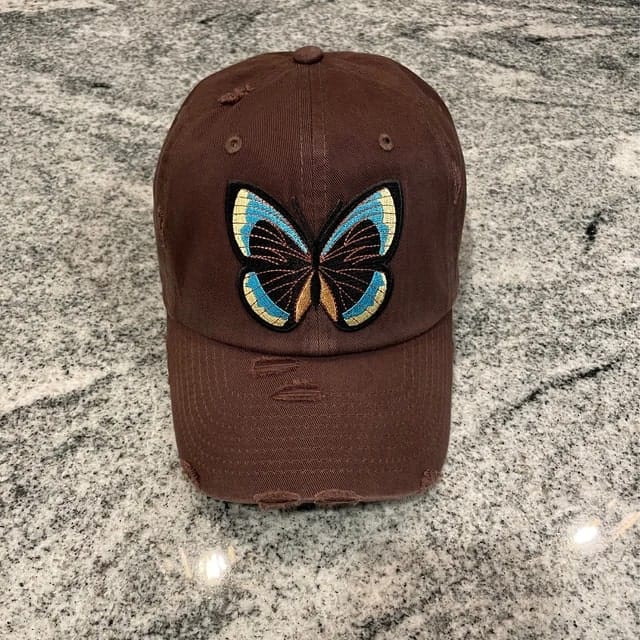 A brown hat with an iron-on butterfly patch.