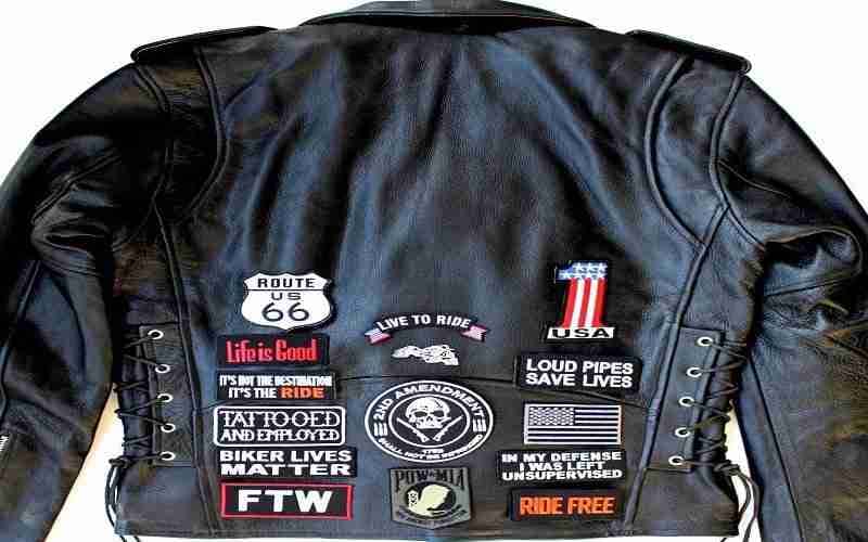 A black leather jacket with many patches on it.