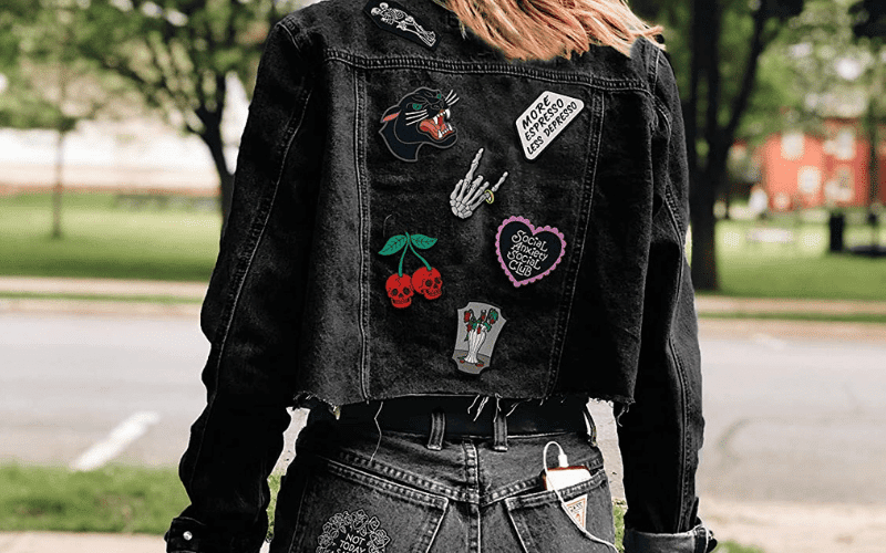 A woman wearing a black denim jacket with patches on it.