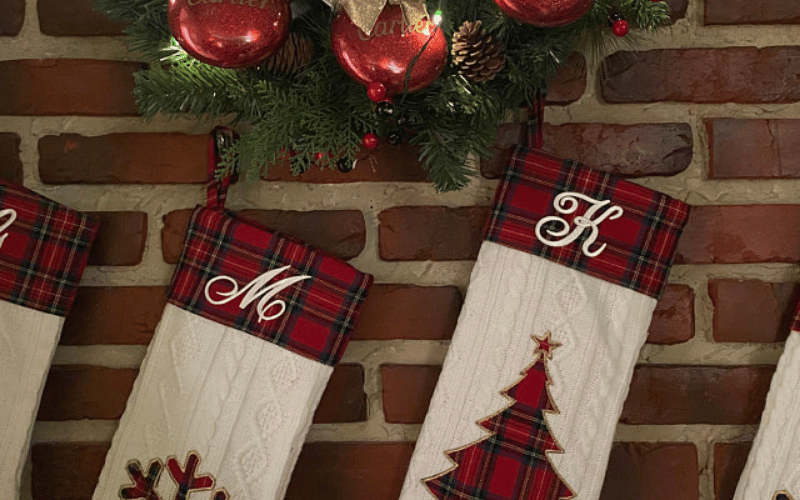 Christmas stockings with monograms hanging on a brick wall.